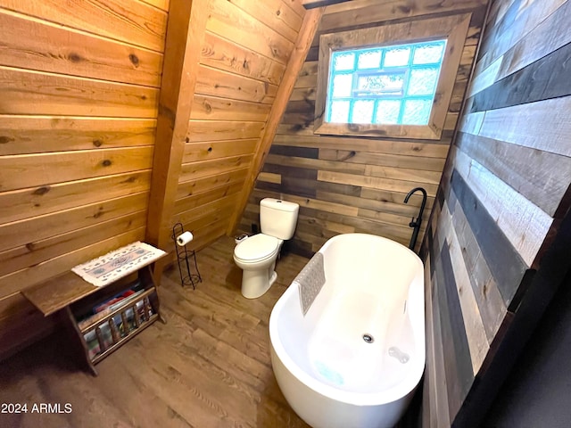 bathroom featuring wood finished floors, toilet, wood walls, and a freestanding bath