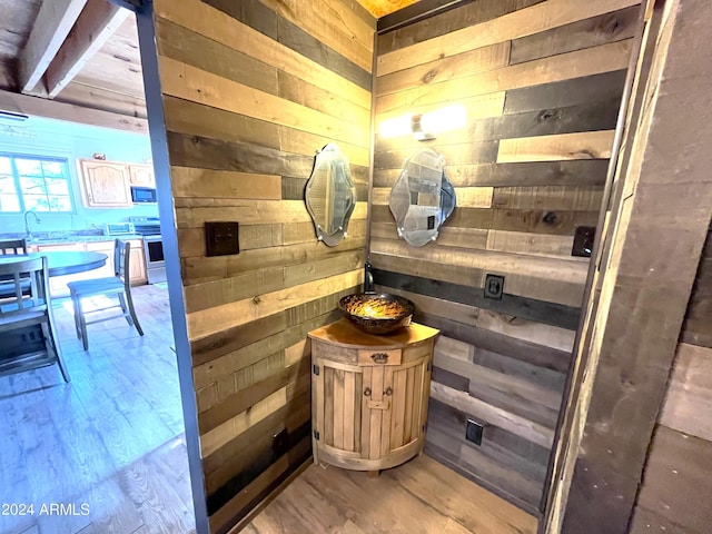 bathroom with wooden walls, wood finished floors, and a sink