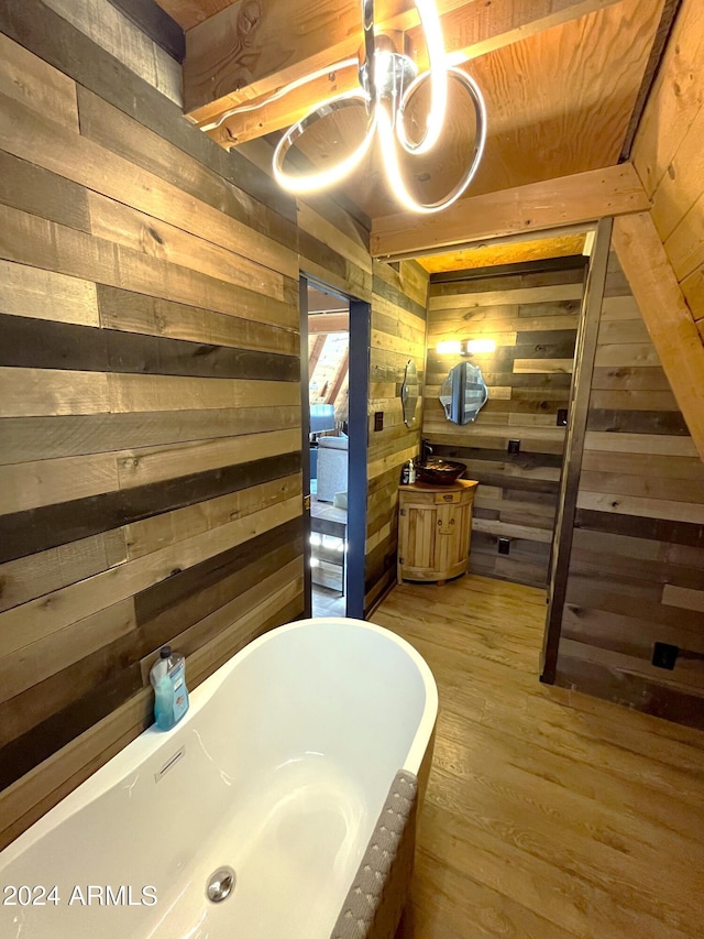 bathroom with vanity, a soaking tub, wood finished floors, and wood walls