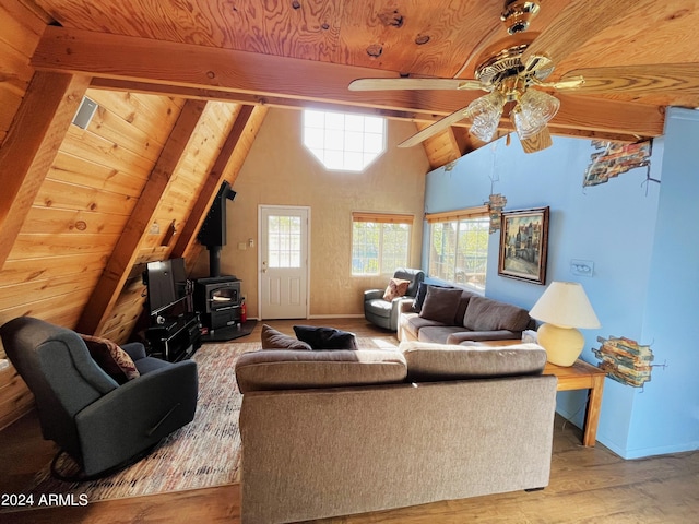 living room featuring vaulted ceiling with beams, wood ceiling, a wood stove, and wood finished floors