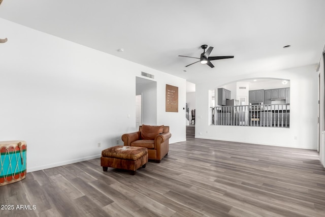 unfurnished room with baseboards, visible vents, arched walkways, ceiling fan, and wood finished floors