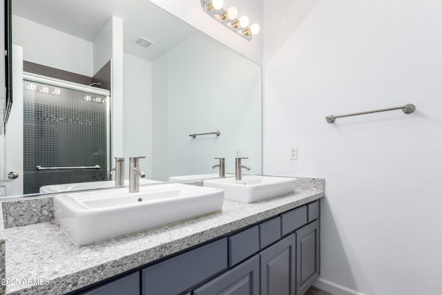 bathroom featuring visible vents, a sink, a shower stall, and double vanity