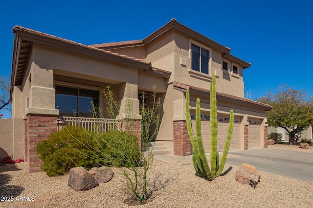 view of front of house with a garage, driveway, brick siding, and stucco siding