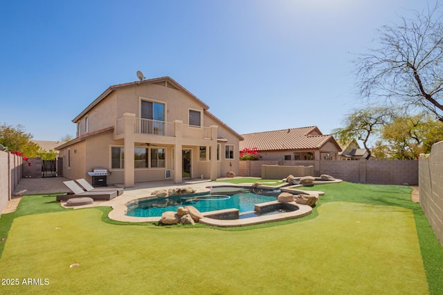 back of house with a fenced backyard, a balcony, a pool with connected hot tub, stucco siding, and a patio area