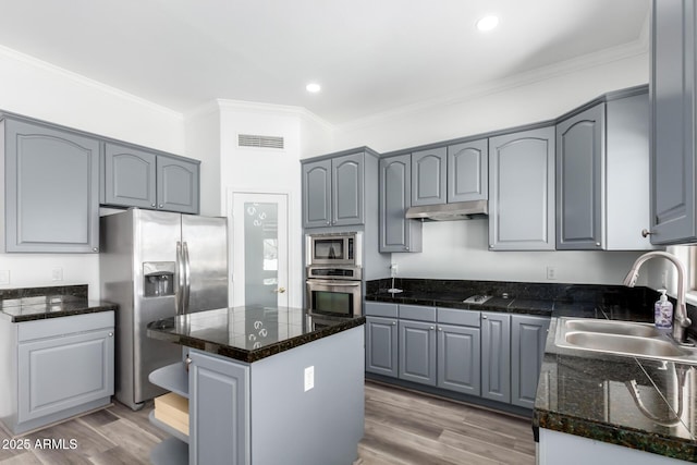 kitchen featuring under cabinet range hood, gray cabinetry, a sink, visible vents, and appliances with stainless steel finishes