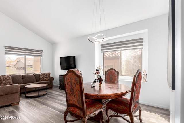 dining space with light wood-style floors, lofted ceiling, and baseboards