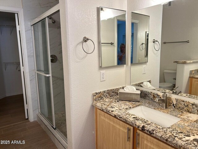 15225 N 100th St Unit 1220, Scottsdale, AZ 85260 - bathroom featuring vanity, a textured wall, wood finished floors, toilet, and a stall shower