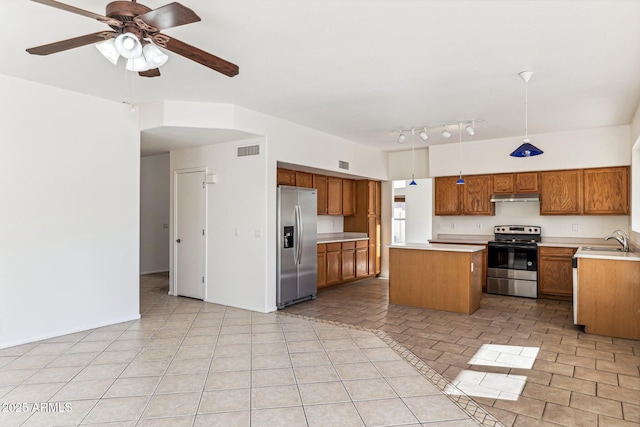 kitchen featuring light tile patterned floors, ceiling fan, appliances with stainless steel finishes, a kitchen island, and pendant lighting