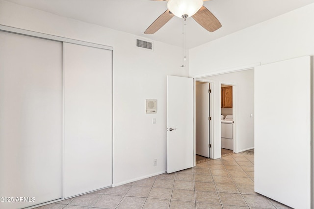 unfurnished bedroom featuring ceiling fan, light tile patterned floors, a closet, and washer / dryer