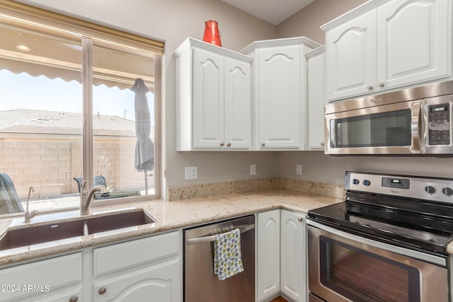 kitchen with light stone counters, sink, white cabinets, and appliances with stainless steel finishes