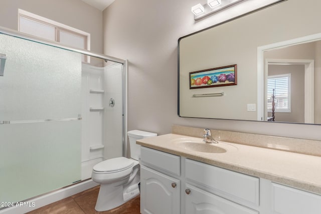 bathroom featuring tile patterned floors, vanity, toilet, and a shower with door