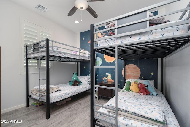 bedroom with wood finished floors, visible vents, and baseboards