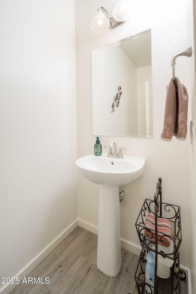 bathroom with a sink, wood finished floors, and baseboards