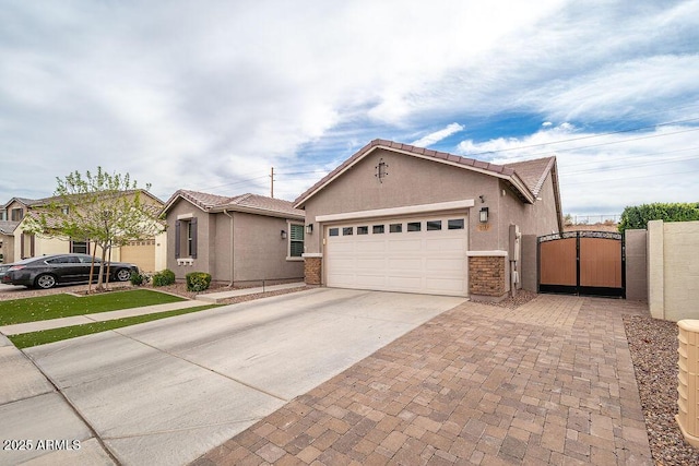 view of front facade featuring a garage, a tiled roof, decorative driveway, a gate, and stucco siding