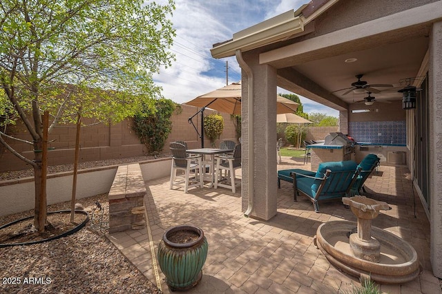 view of patio featuring outdoor dining area, a fenced backyard, and a ceiling fan