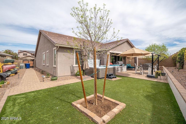 rear view of house with a patio area, a yard, a fenced backyard, and stucco siding