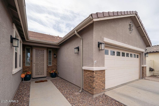 doorway to property featuring concrete driveway, an attached garage, and stucco siding