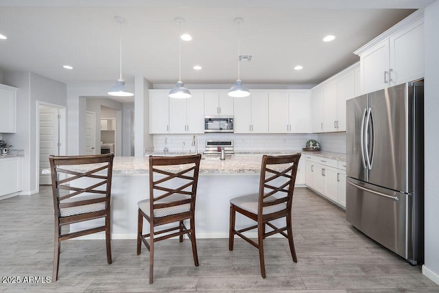 kitchen with visible vents, light wood-style flooring, stainless steel appliances, white cabinetry, and backsplash