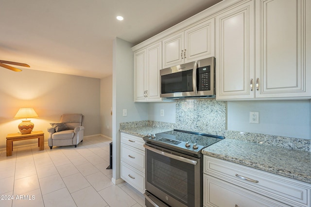 kitchen featuring stainless steel appliances, backsplash, light tile patterned floors, white cabinetry, and light stone counters