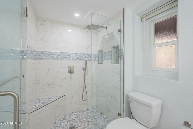 bathroom featuring a shower with door and toilet