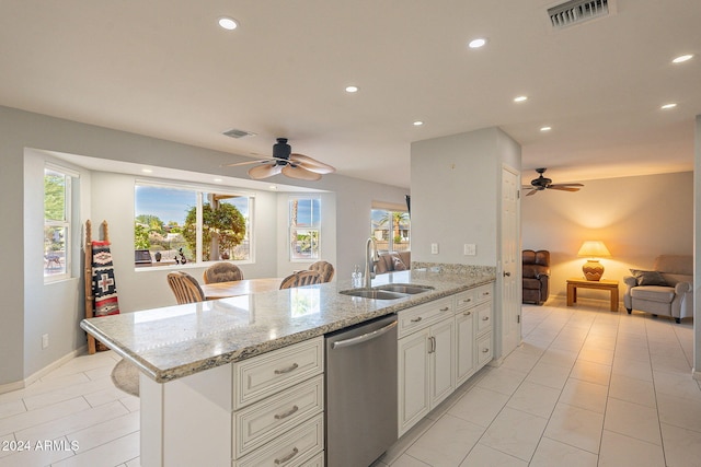 kitchen with dishwasher, a kitchen breakfast bar, sink, white cabinetry, and light stone counters