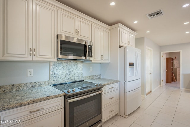 kitchen featuring light stone counters, appliances with stainless steel finishes, light tile patterned floors, and backsplash