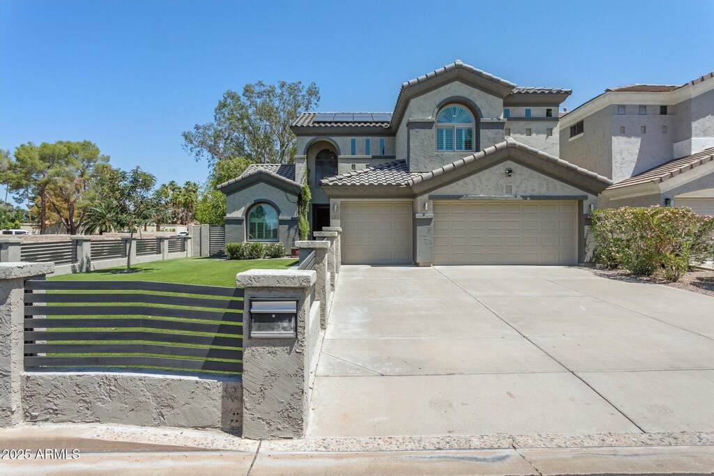 3202 E Orange Dr, Phoenix, AZ 85018 - view of front of property featuring solar panels, concrete driveway, stucco siding, a tiled roof, and an attached garage