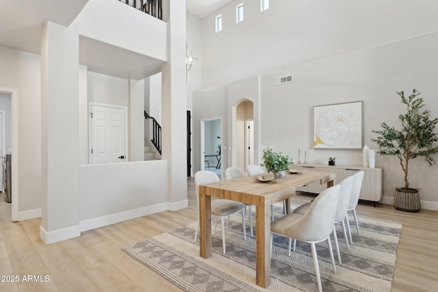 3202 E Orange Dr, Phoenix, AZ 85018 - dining room with light wood-type flooring, stairs, arched walkways, baseboards, and a high ceiling