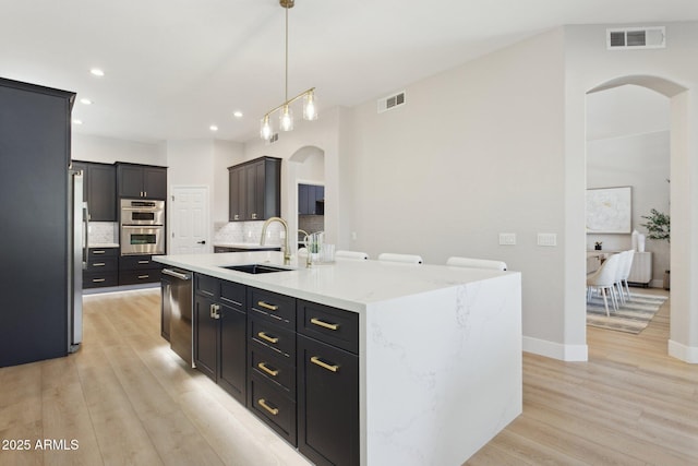 3202 E Orange Dr, Phoenix, AZ 85018 - kitchen with arched walkways, appliances with stainless steel finishes, a sink, light wood-type flooring, and recessed lighting