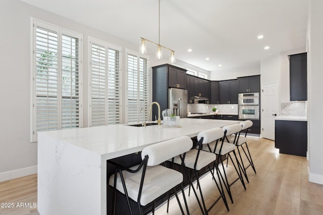3202 E Orange Dr, Phoenix, AZ 85018 - kitchen with appliances with stainless steel finishes, a sink, decorative backsplash, light wood-style flooring, and a breakfast bar