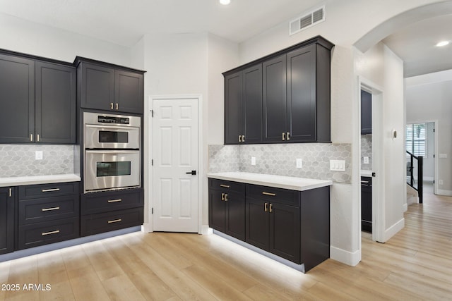 3202 E Orange Dr, Phoenix, AZ 85018 - kitchen featuring stainless steel double oven, arched walkways, light wood-style floors, light countertops, and recessed lighting