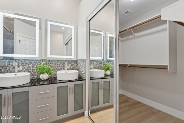 3202 E Orange Dr, Phoenix, AZ 85018 - full bath featuring double vanity, wood finished floors, a walk in closet, tasteful backsplash, and baseboards