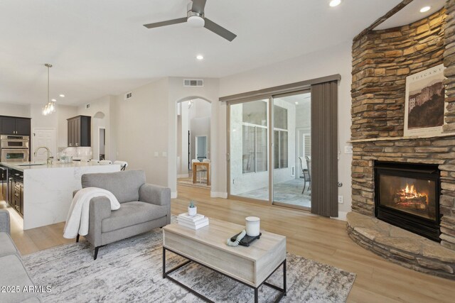 3202 E Orange Dr, Phoenix, AZ 85018 - living room featuring a fireplace, a ceiling fan, arched walkways, light wood finished floors, and recessed lighting