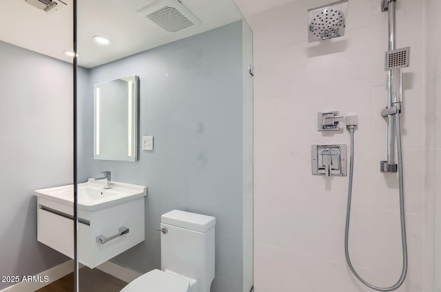 bathroom featuring vanity, toilet, and a tile shower