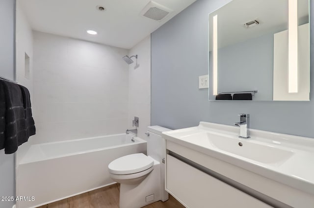 full bathroom featuring hardwood / wood-style flooring, vanity, tiled shower / bath, and toilet