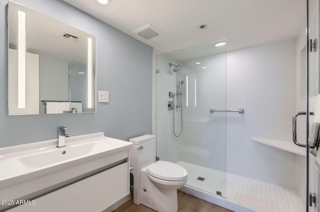 bathroom with vanity, a shower with shower door, and toilet