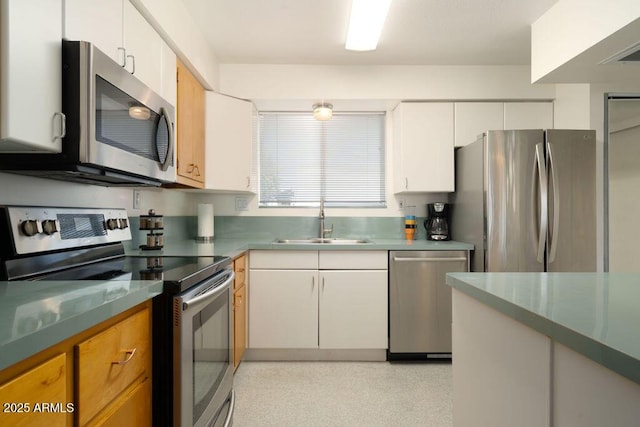 kitchen featuring appliances with stainless steel finishes, a sink, and white cabinets