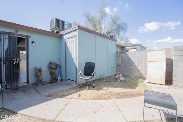 view of patio featuring an outbuilding, a shed, central AC, and fence