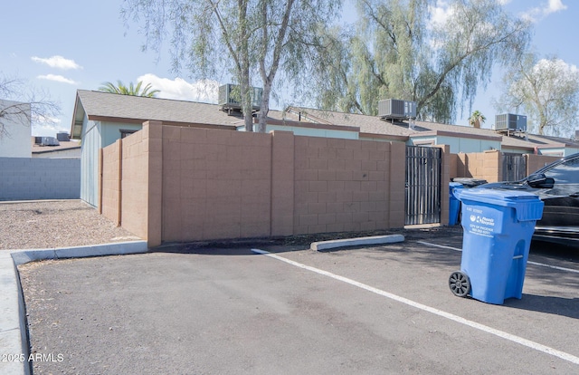uncovered parking lot featuring a gate and fence
