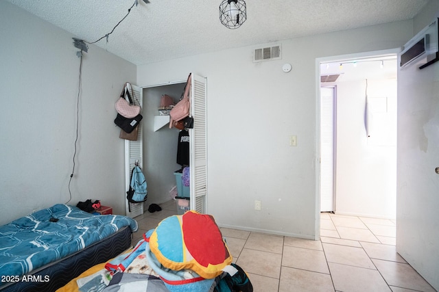 bedroom with light tile patterned floors, visible vents, and a textured ceiling