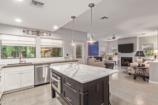 kitchen featuring white cabinetry, sink, ceiling fan, pendant lighting, and appliances with stainless steel finishes