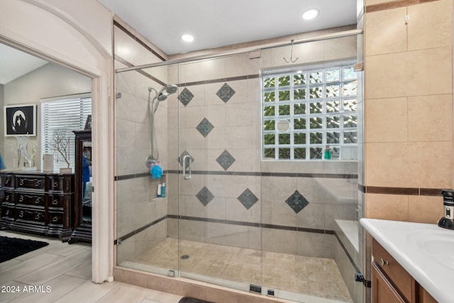 bathroom with tile patterned flooring, vanity, a shower with shower door, and vaulted ceiling