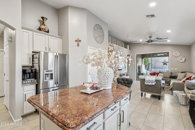 kitchen featuring stone counters, stainless steel refrigerator with ice dispenser, white cabinetry, and a kitchen island