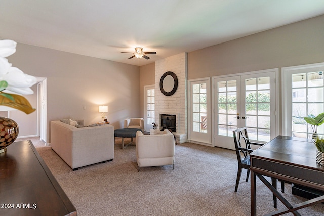 living room featuring ceiling fan, french doors, light colored carpet, and a brick fireplace