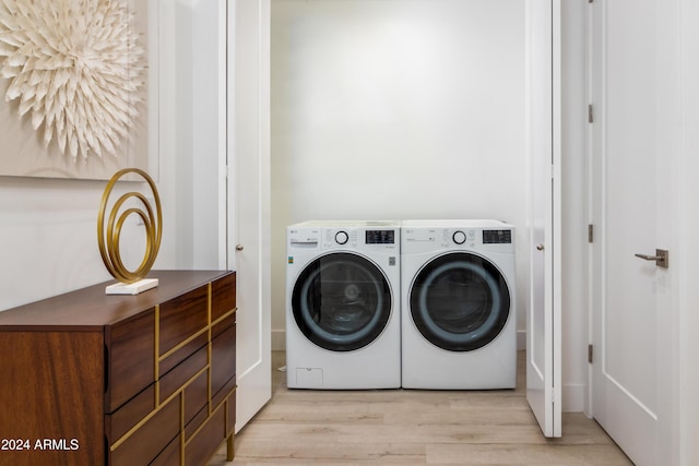 laundry room featuring washing machine and clothes dryer and light hardwood / wood-style flooring