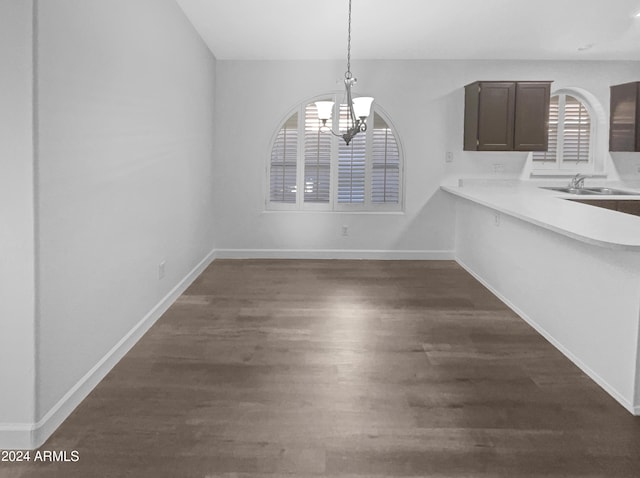 unfurnished dining area featuring sink, dark hardwood / wood-style floors, and a notable chandelier