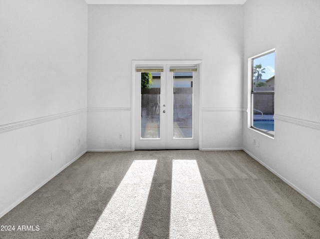 carpeted empty room with a healthy amount of sunlight and french doors