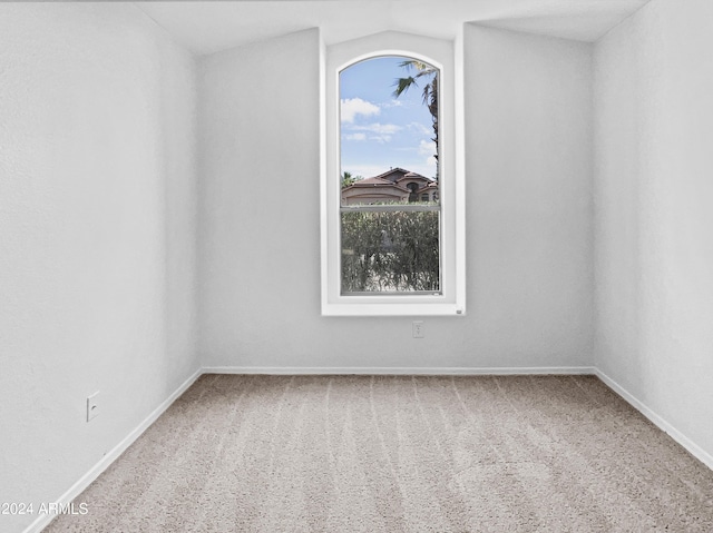 carpeted empty room with lofted ceiling