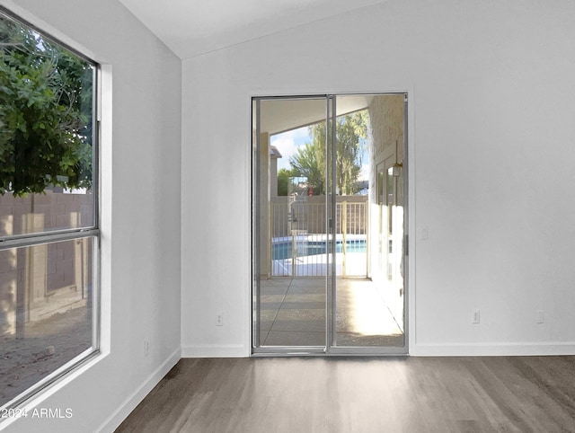 unfurnished room featuring hardwood / wood-style flooring and vaulted ceiling