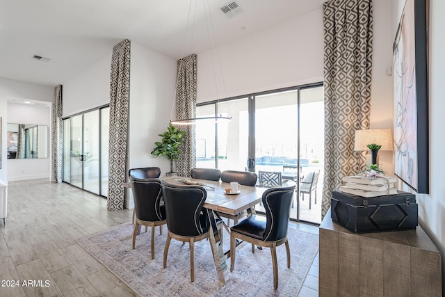 dining room with a towering ceiling, wood finished floors, and visible vents